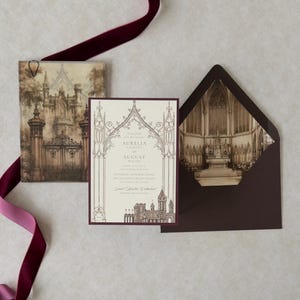 Bitter Chocolate wedding envelope opened to reveal a dramatic Gothic architectural interior liner, displayed with Aurelia's ivory invitation, castle-gate artwork, coordinating details card, and rich burgundy decorative accents.