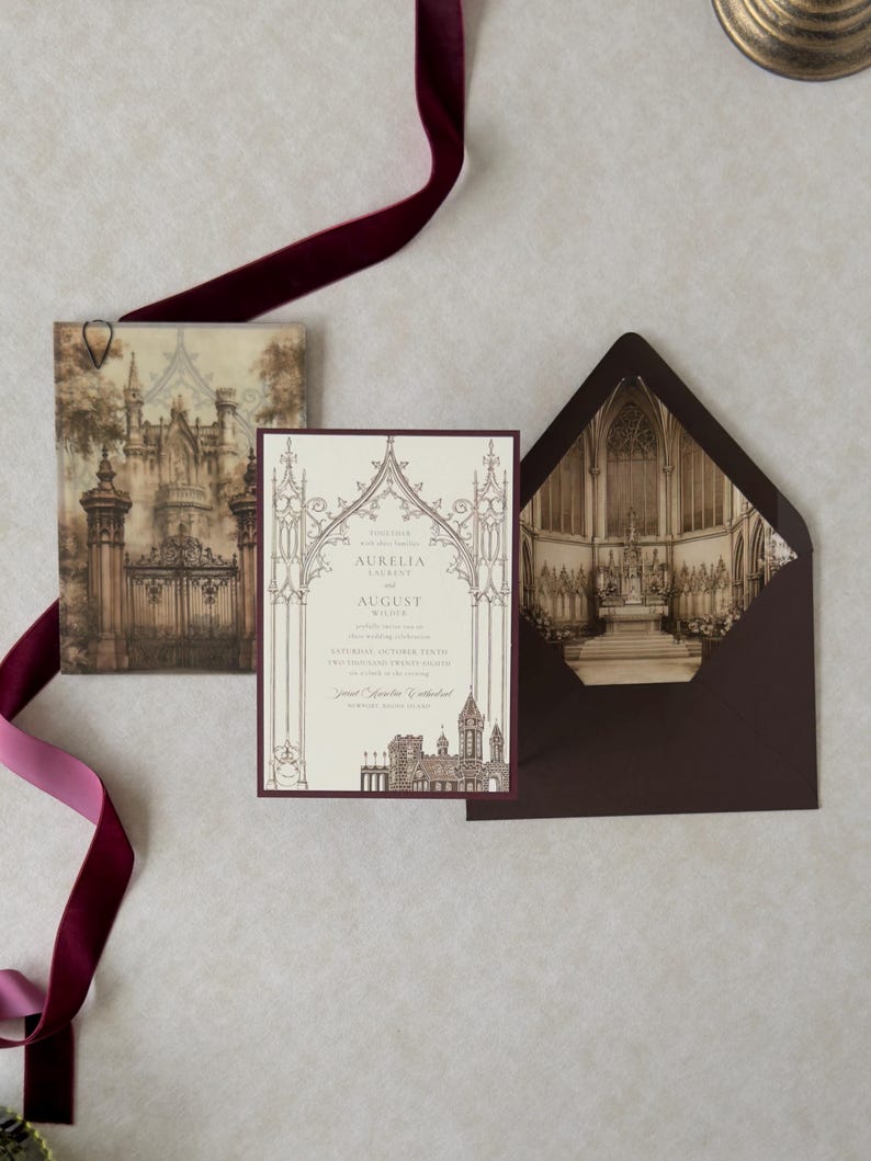 Bitter Chocolate wedding envelope opened to reveal a dramatic Gothic architectural interior liner, displayed with Aurelia's ivory invitation, castle-gate artwork, coordinating details card, and rich burgundy decorative accents.