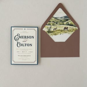 Western wedding invitation paired with translucent layered stationery tied with thin brown ribbon, featuring dusty blue and warm neutral details for an elegant ranch wedding.