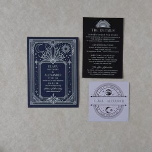 Elara celestial wedding stationery collection arranged in a flat lay, showing the navy invitation with silver geometric sun and moon border, black details card with white ink, and lavender celestial tag.