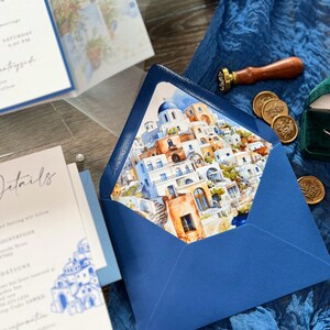 May include: A blue envelope with a watercolor illustration of a white and blue Greek village on the front. The envelope is decorated with a wax seal.