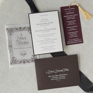 Romantic dark academia wedding stationery with an ivory invitation, burgundy bookmark with gold tassel, ornate decorative card, and coordinating dark envelope, featuring a vintage literary wedding aesthetic.