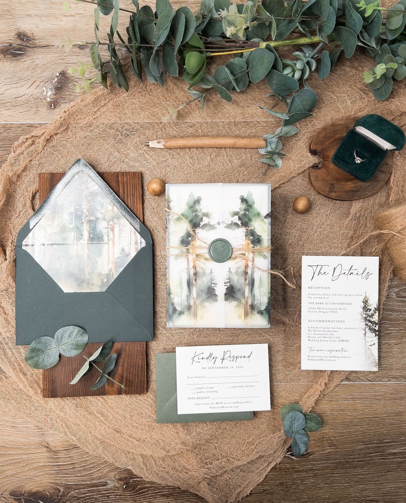 May include: A wedding invitation suite featuring a watercolour forest design. The invitation includes a green and brown envelope with a wax seal. The RSVP card has a green envelope and the details card features a watercolour forest design.