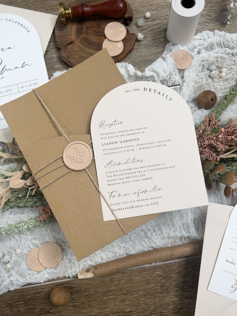 May include: A wedding invitation suite with a brown envelope, a white card with the text "All the Details" and a cream card with the text "Reception" and "Accommodations". The cream card has a wax seal with a floral design.