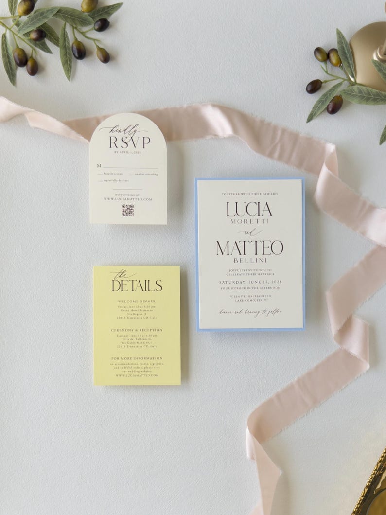 Pale blue layered Lucia wedding invitation paired with butter yellow details card and ivory arch RSVP card, featuring delicate typography and soft pastel colors.