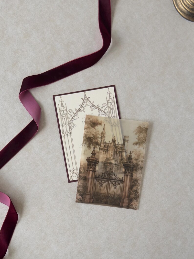 Illustrated Gothic castle entrance on translucent vellum displayed over a Wedding Cream invitation with Bitter Chocolate backing, styled with rich burgundy ribbon and antique architectural stationery details.