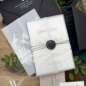 May include: Elegant wedding invitation suite featuring a frosted invitation with a mountain scene, sealed with a black wax stamp. Includes black envelopes and RSVP cards. The suite is tied with black twine and includes the text "THE FUTURE MR. & MRS."