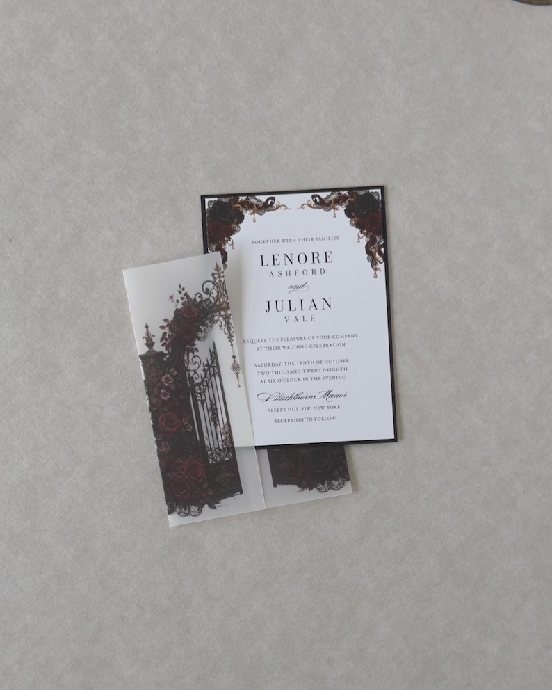 White Lenore wedding invitation featuring refined serif typography and romantic Gothic styling, displayed over dark floral vellum artwork on a neutral textured background.