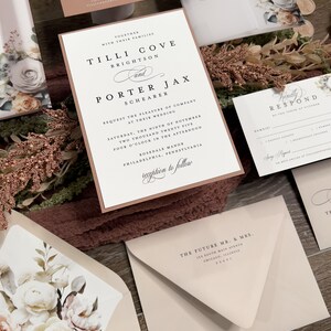 Romantic estate wedding invitation suite with soft floral artwork and warm neutral stationery.