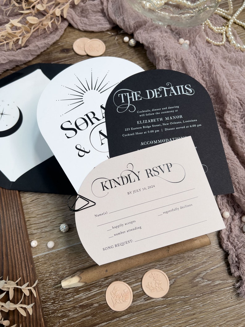 May include: A wedding invitation suite with a black and white design. The invitation features a sunburst design and the text "SORA & A". The details card features the text "THE DETAILS" and includes the wedding date, time, and location. The RSVP card features the text "KINDLY RSVP" and includes a space for guests to RSVP by July 10, 2024.