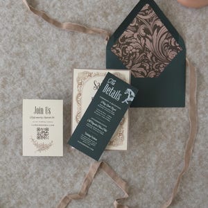 Vintage-inspired Sadie wedding invitation suite with dark green envelope opened to reveal a romantic floral patterned liner, paired with ivory and green stationery.