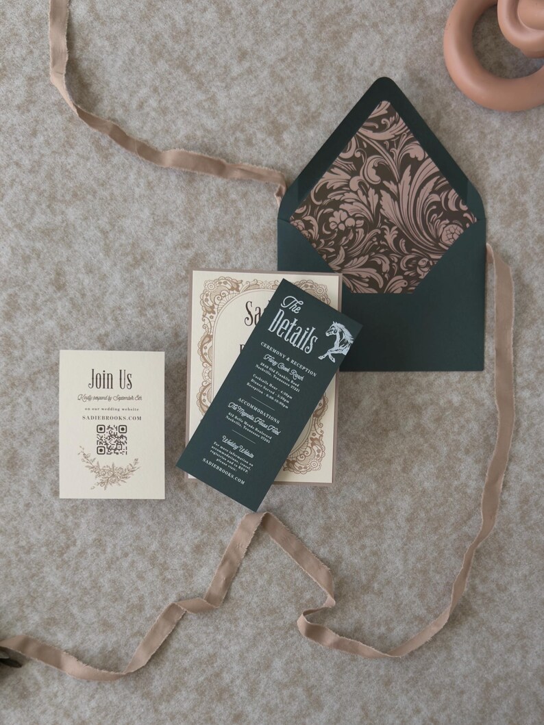 Vintage-inspired Sadie wedding invitation suite with dark green envelope opened to reveal a romantic floral patterned liner, paired with ivory and green stationery.