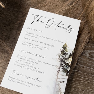 May include: A white wedding invitation card with black text. The card features a watercolour illustration of a snowy forest scene with pine trees. The text reads "The Details", "Reception", "Cocktails, dinner and dancing will follow the ceremony at", "THE BARN AT COUNTRYSIDE", "15243 NE Countryside Drive", "Aurora, Oregon 97002", "ACCOMMODATIONS", "A block of rooms has been reserved at", "The Hilton Garden Inn", "at a discounted rate", "Please call 800.233.1234", "Wedding Group Code: SAWED", "For more information", "Please visit our wedding website: PadmaandHarrison.co".