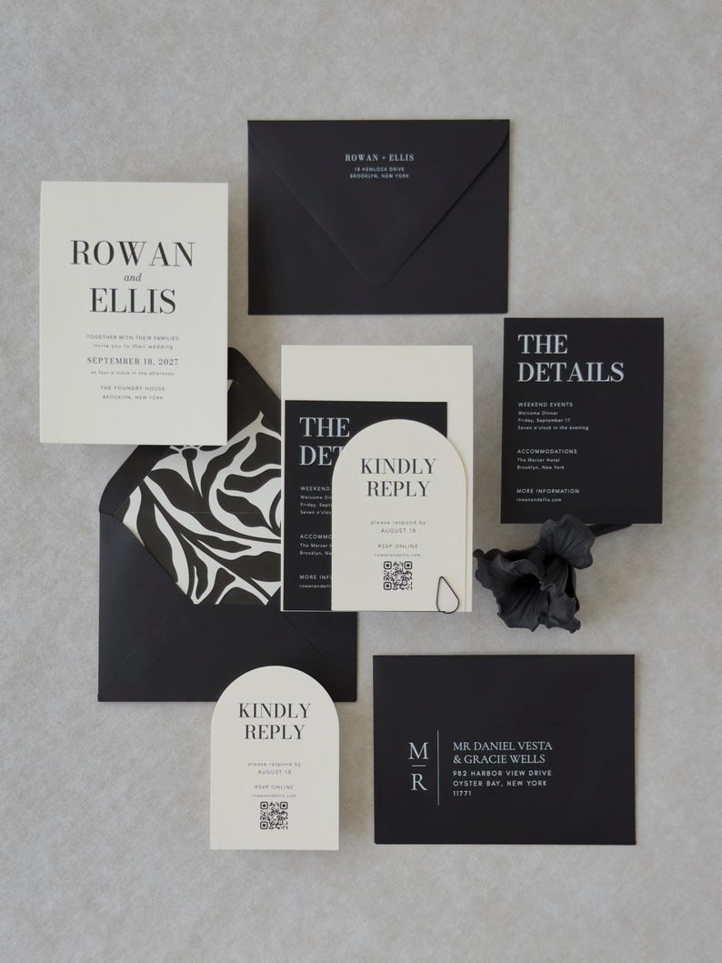 Black and ivory wedding invitation suite styled on a neutral textured background with elegant modern details