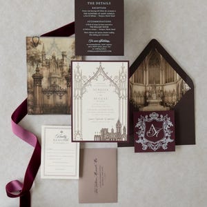Aurelia Gothic wedding stationery featuring a cream invitation with intricate architectural artwork, Bitter Chocolate backing mat and envelope, antique-inspired Gothic interior liner, Claret decorative crest tag, and traditional RSVP stationery.