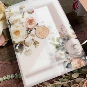 Neutral floral wedding invitation with vellum wrap, wax seal and soft botanical artwork.