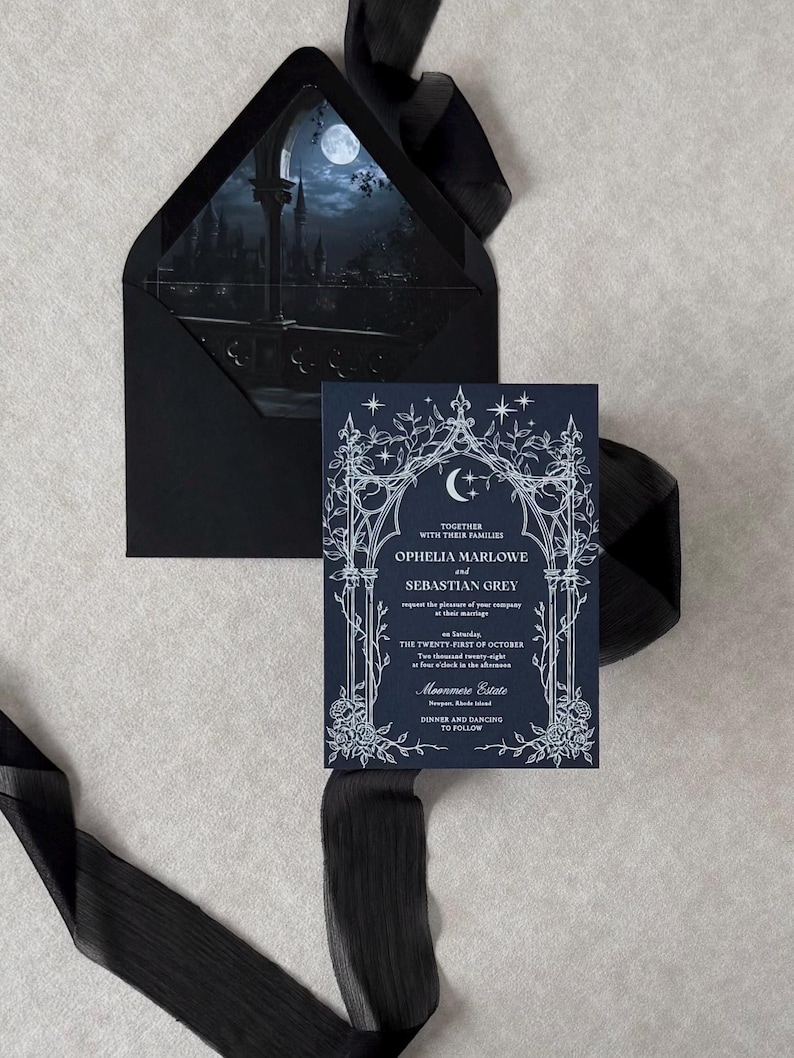 Imperial Navy wedding invitation featuring intricate white ink Gothic botanical artwork, displayed in front of an Ebony envelope with a dark blue moonlit castle liner and coordinating black ribbon.