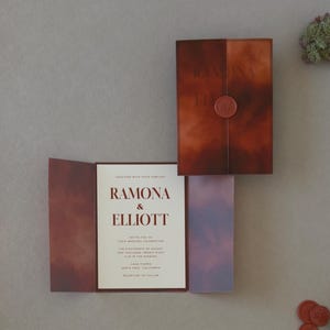 Modern rust and brown Ramona wedding invitation suite featuring a layered ivory invitation, dark chocolate RSVP card and artistic terracotta stationery details.