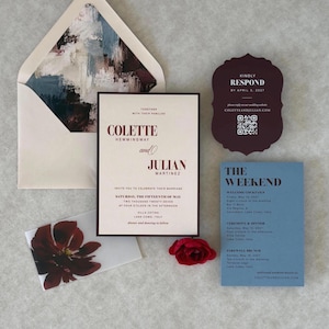 Romantic burgundy, dusty blue and ivory wedding invitation suite arranged with a floral-lined burgundy envelope, ivory floral invitation, dusty blue details card and burgundy scalloped RSVP card.