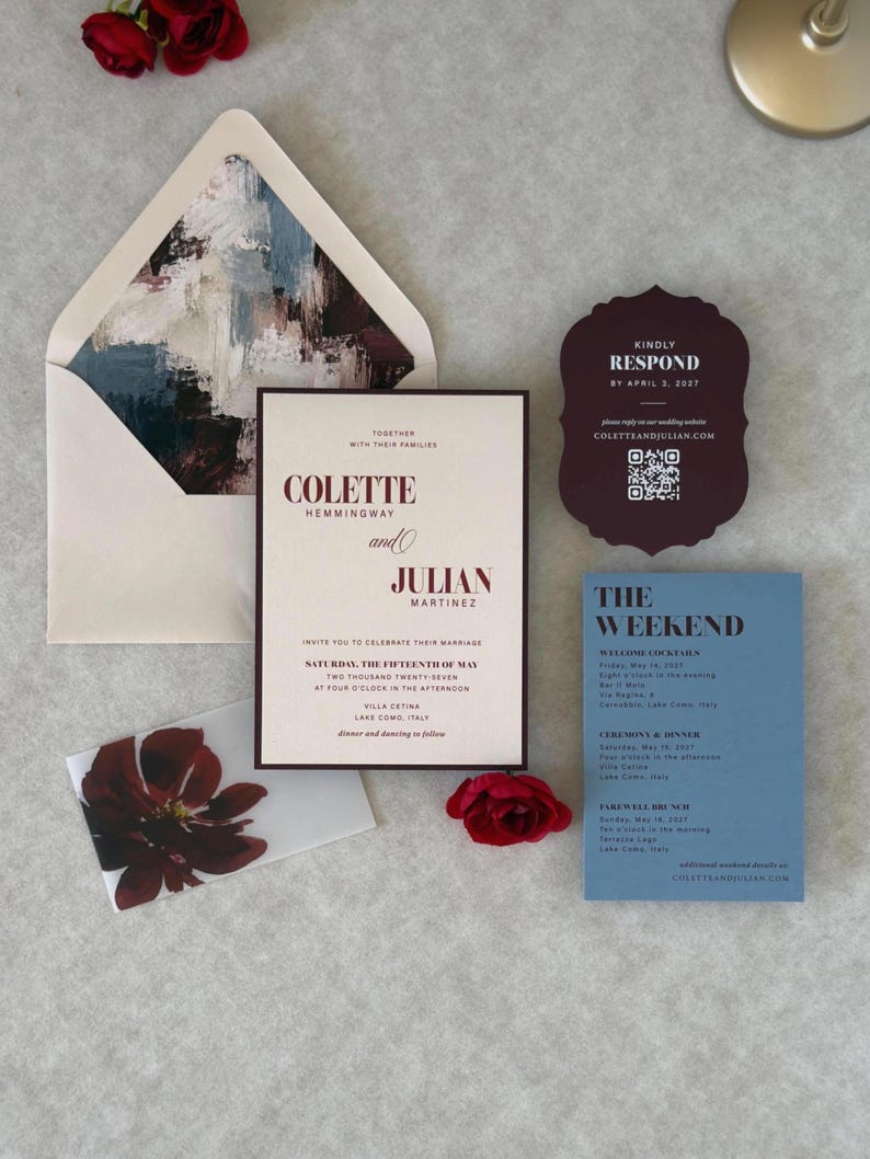 Romantic burgundy, dusty blue and ivory wedding invitation suite arranged with a floral-lined burgundy envelope, ivory floral invitation, dusty blue details card and burgundy scalloped RSVP card.