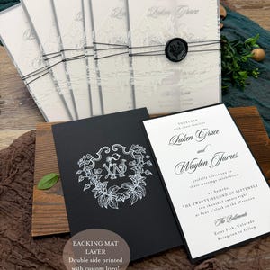 May include: Wedding invitation suite featuring a black and white design. The suite includes invitations with a mountain landscape, a black card with a floral monogram, and a white invitation with elegant script. The text reads "Laken Grace and Waylon James".