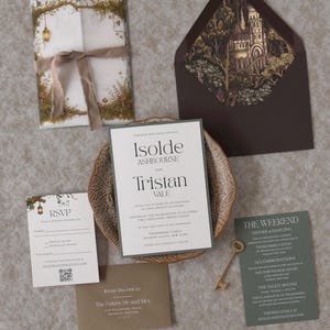May include: A wedding invitation suite featuring a main card for Isolde Ashbourne and Tristan Vale, an RSVP card, a weekend itinerary card, a small envelope, and a large envelope with a castle illustration, tied with a ribbon and a key.