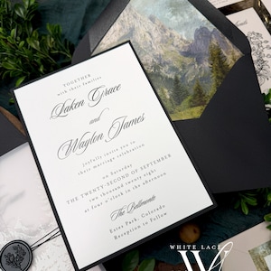 May include: Elegant wedding invitation suite featuring a black and white design. The invitation card includes the names "Laken Grace and Waylon James" and event details. The envelope has a mountain landscape. A wax seal and greenery add to the aesthetic.