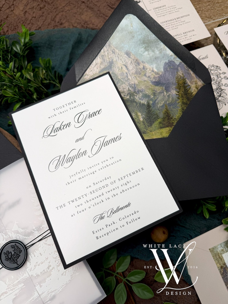 May include: Elegant wedding invitation suite featuring a black and white design. The invitation card includes the names "Laken Grace and Waylon James" and event details. The envelope has a mountain landscape. A wax seal and greenery add to the aesthetic.