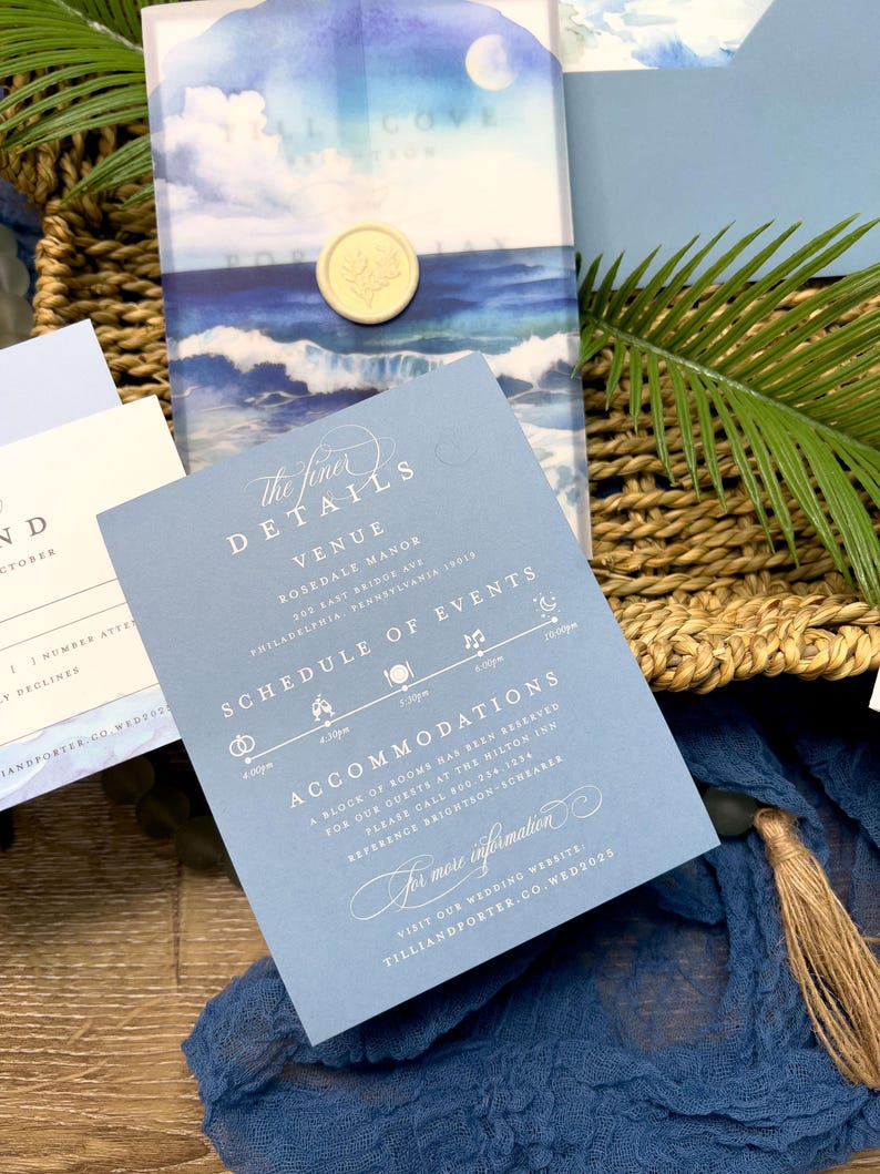 May include: Wedding invitation suite featuring a blue and white watercolor design with ocean waves and a full moon. The invitation includes details about the venue, schedule of events, and accommodations. A gold wax seal adds an elegant touch.