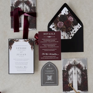 Lenore wedding invitation suite arranged with white invitation, Ebony backing mat, Claret details card, Dark Grey tombstone-shaped RSVP, illustrated floral vellum jacket, and black envelope with dramatic rose liner.