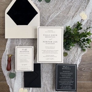 May include: Black and white wedding invitation suite with a white envelope, a black inner envelope, and three cards. The main card features the couple's names, wedding date, and location. The second card is a response card with a black border and white text. The third card is a details card with a black border and white text.