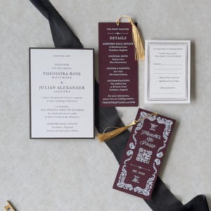 Theodora wedding invitation suite featuring elegant ivory invitation typography, burgundy bookmark with gold tassel, antique-style decorative cards, and coordinating dark brown stationery against a neutral background.