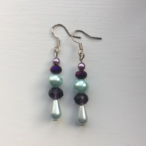 May include: A pair of dangle earrings with light blue, purple, and iridescent beads.