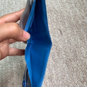 May include: A blue waterproof pouch with a clear plastic window. The pouch is open and folded in half, revealing the blue interior.