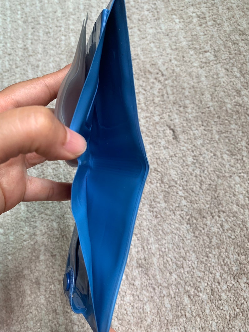 May include: A blue waterproof pouch with a clear plastic window. The pouch is open and folded in half, revealing the blue interior.