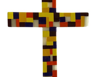 May include: A colorful glass cross made of small squares in shades of yellow, orange, red, blue, white, and brown. The cross is hanging from a brown cord.