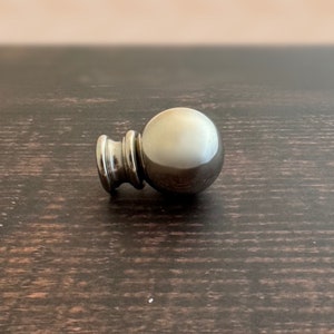 May include: A silver metal finial with a round ball shape.