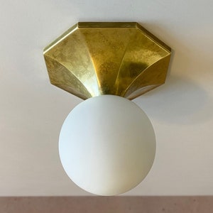 May include: A gold ceiling light fixture with an octagonal base and a white frosted glass globe.