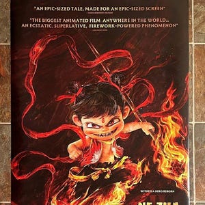 May include: Poster for "Ne Zha II" featuring a cartoon character with fiery hair and flames. The poster has text that reads "The Global Phenomenon Returns to Theaters" and "Coming Soon A24."