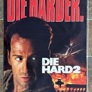 May include: Movie poster for "Die Hard 2" featuring Bruce Willis. The title "DIE HARDER" is in large red letters above the title "DIE HARD 2". An airplane flies over a burning airport.