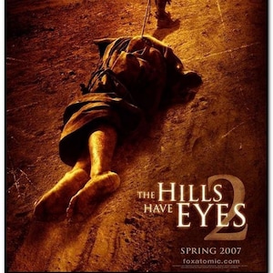 May include: Movie poster for the horror film "The Hills Have Eyes 2". The poster features a man dragging a bound and unconscious person through a desert landscape. The text "The Hills Have Eyes 2" is in large, bold letters at the bottom of the poster.