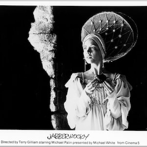 May include: A black and white photo of a woman wearing a white dress and a large, star-shaped hat. The woman is holding a heart in her hands. The text "JABBERWOCKY" is written at the bottom of the photo.