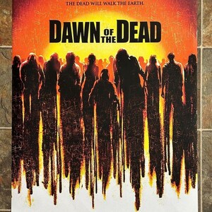 May include: A movie poster for Dawn of the Dead featuring a crowd of dark silhouettes against a bright yellow and orange sun. The text reads: When there's no more room in hell, the dead will walk the earth. Dawn of the Dead, with production credits.