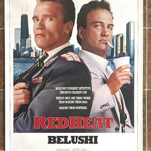 May include: Film poster for "Red Heat" starring Arnold Schwarzenegger and James Belushi. The poster displays a cityscape and the text: "Moscow's toughest detective, Chicago's craziest cop."