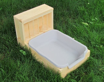 May include: A wooden cat litter box with a removable lid and a white plastic litter tray. The box is made of natural wood and has a rustic look.