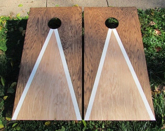 May include: Two wooden game boards with white triangle targets and a circular hole in the center. The boards are stained a dark brown color.