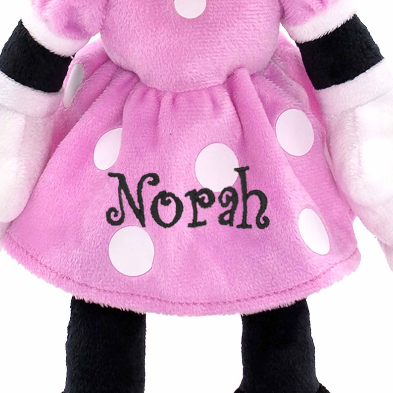 May include: Pink plush Minnie Mouse doll with white polka dots and the name "Norah" embroidered on the dress.