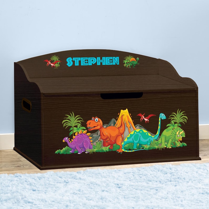 May include: A brown wooden toy chest with a dinosaur theme. The chest has a hinged lid and a personalized nameplate that reads "STEPHEN". The front of the chest features a colorful illustration of dinosaurs, a volcano, and palm trees.