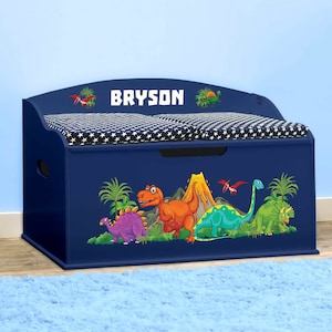 May include: Blue wooden toy chest with a padded lid and a dinosaur design. The lid has a white star pattern and the text "BRYSON" is printed on the front.