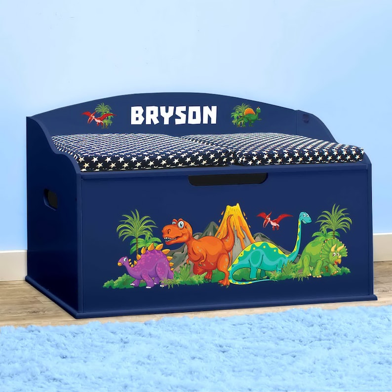 May include: Blue wooden toy chest with a padded lid and a dinosaur design. The lid has a white star pattern and the text "BRYSON" is printed on the front.